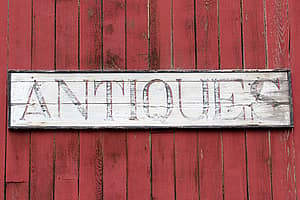worn antiques sign on the side of a shop