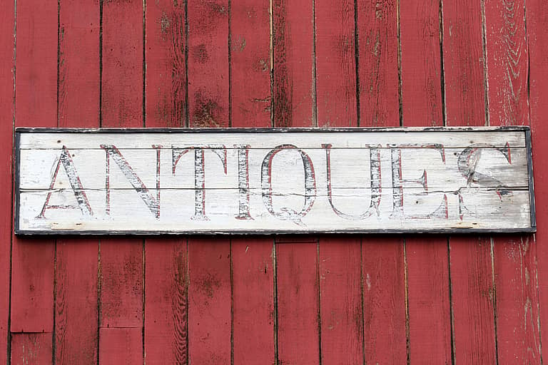 worn antiques sign on the side of a shop