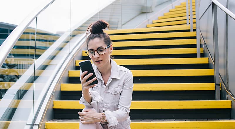 woman in casual clothes reads a website on her smartphone
