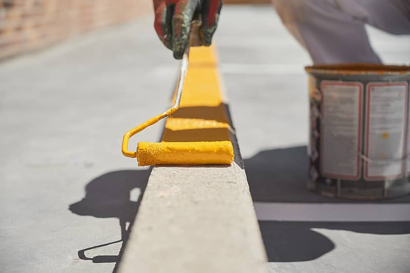 closeup of employee painting curb