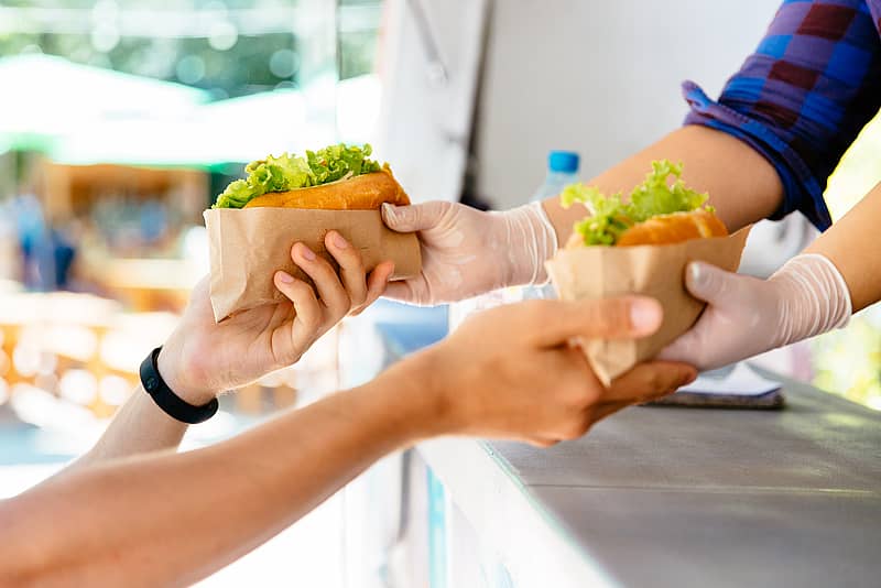 close up of a customer purchasing sandwiches from a food truck vendor 