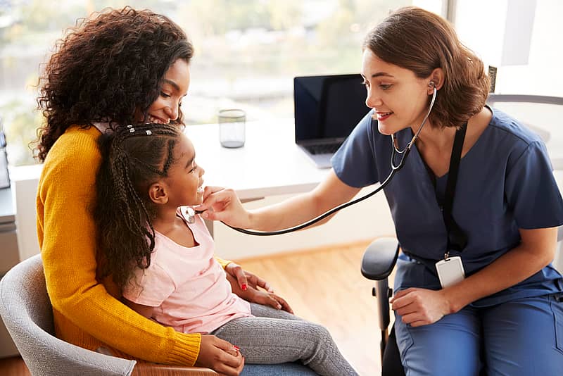 female pediatrician performing check-up for a young girl and mother