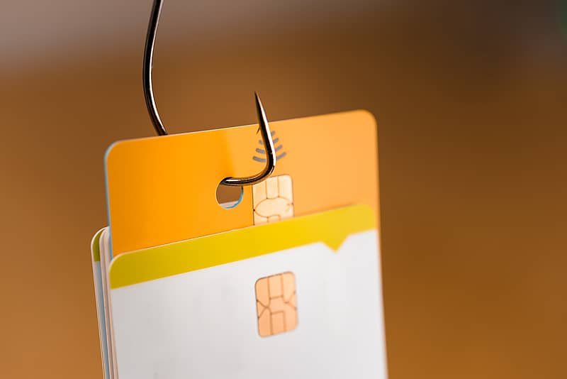 a fishing hook grabs a credit card from a stack of other cards 