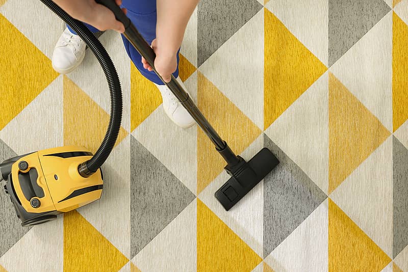 a person cleaning a gray and yellow carpet 