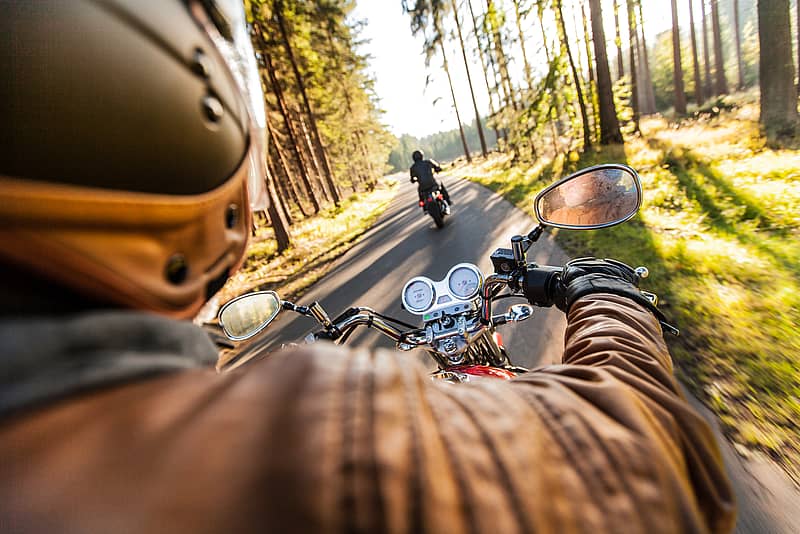 couple riding motorcycles on road in wooded area
