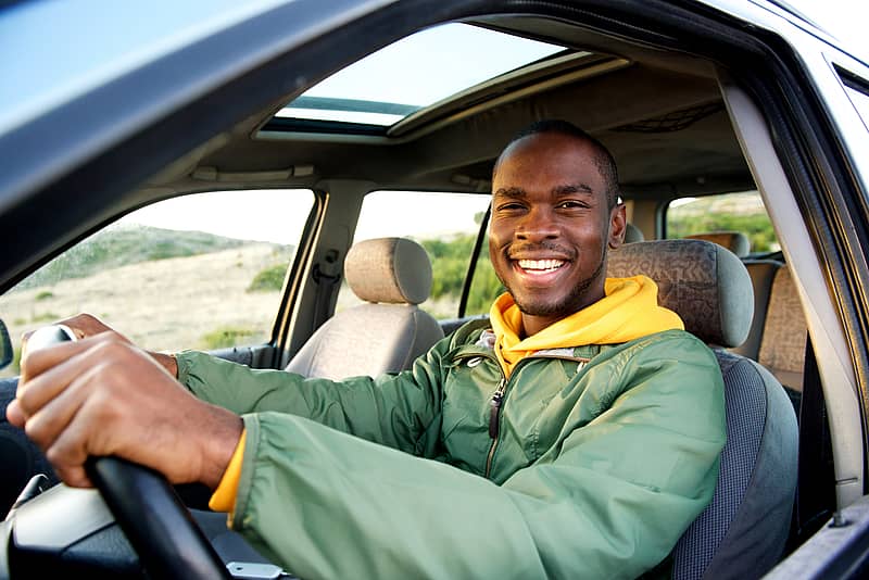 male teenage driver smiling as he drives through the countryside
