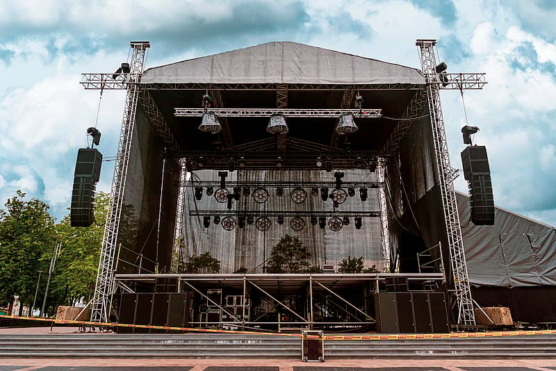 outdoor concert venue set up with stage, speakers, and lighting