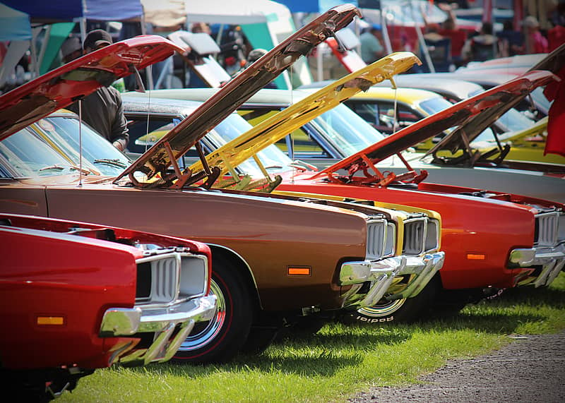row of classic cars at a car show during sunny weather