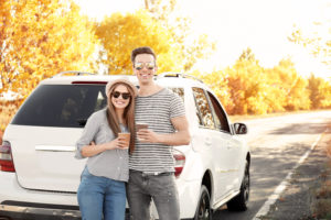 couple standing outside car holding coffee
