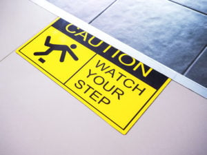 "Caution watch your step" on yellow and black warning sticker 
