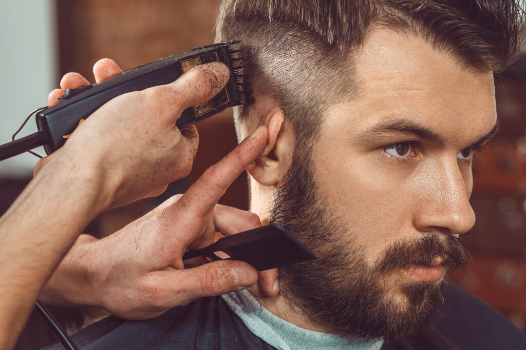 a barber uses clippers to trim a client's hair 