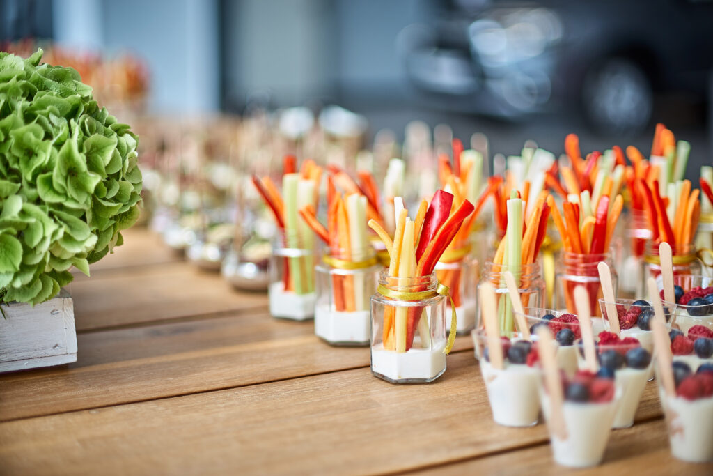 fruit and veggie appetizers sit on a table at a catered event 