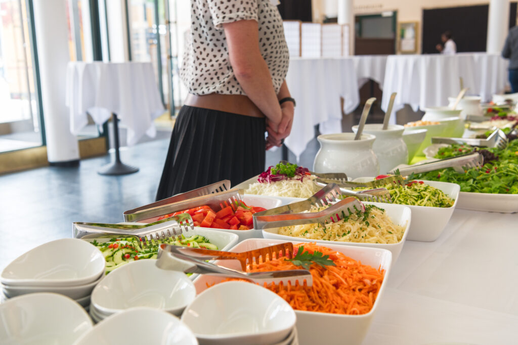 a catering employee stands behind a buffet at a corporate event 