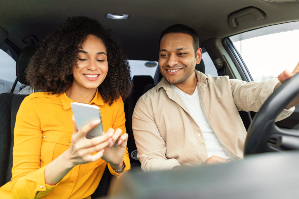 couple sitting in interior of used car looking at a cell phone and smiling